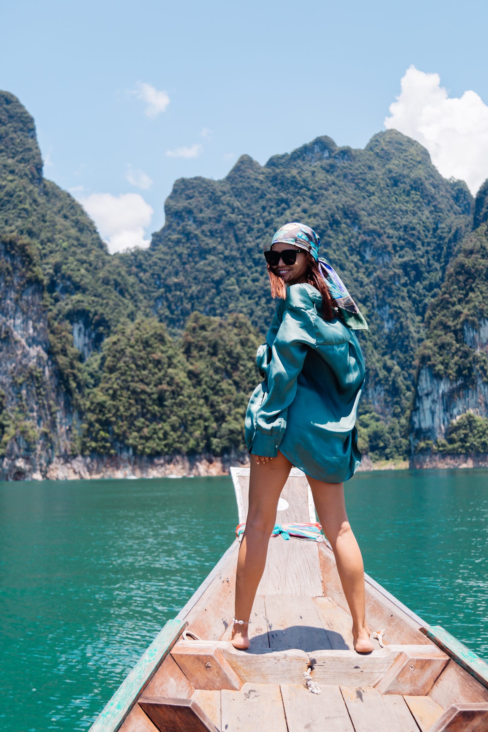 young asian happy woman blogger tourist silk suit scarf sunglasses vacation travel around thailand asian boat khao sok national park
